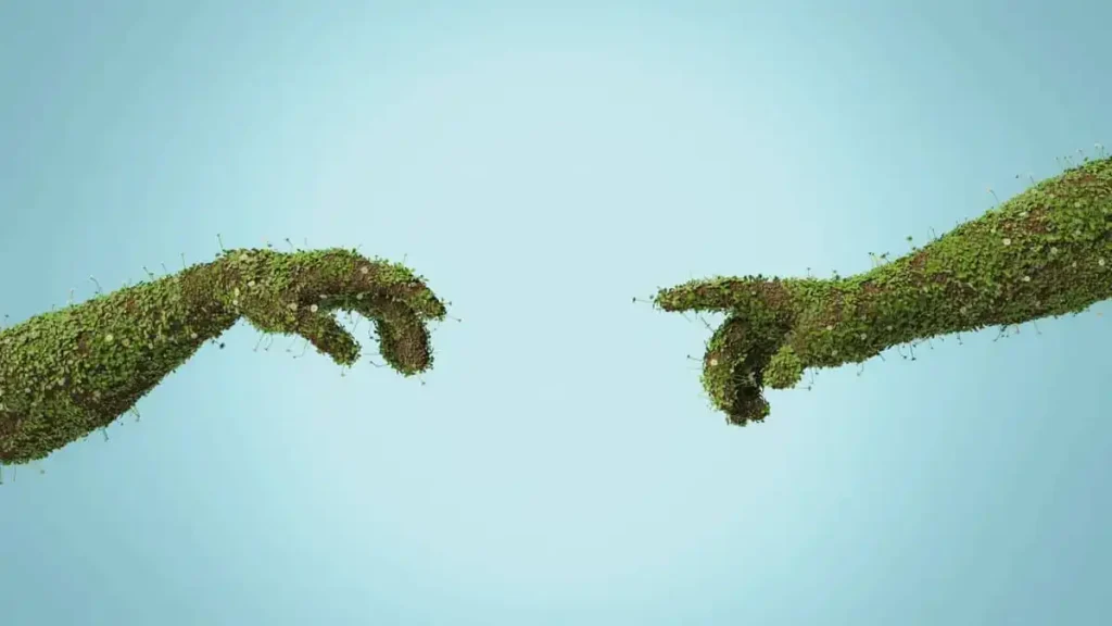 Artistic: two hands made of soil and plants reaching out to touch each other. Blue background