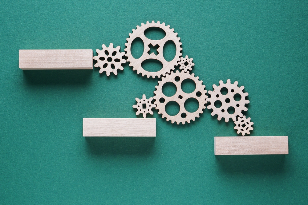 Artistic: wooden gears and blocks sitting on a green background