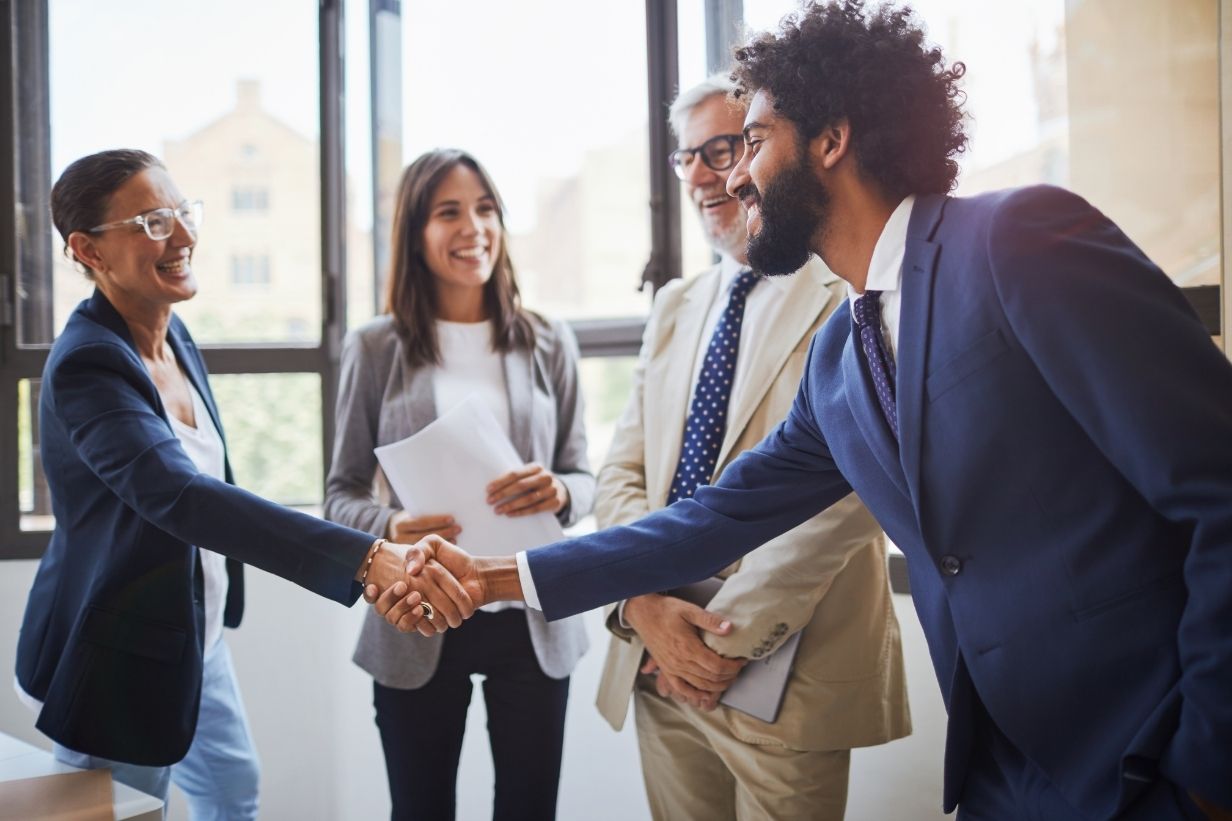 Business meeting handshake. 4 climate professionals in dress clothes